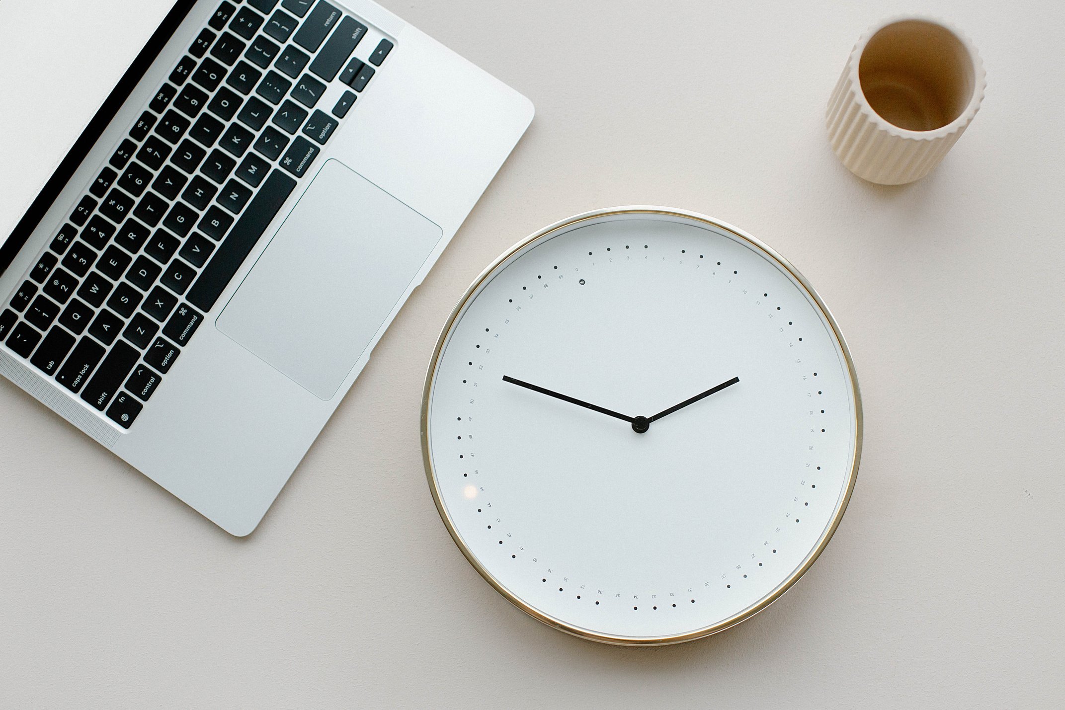 Close-Up Shot of an Analog Clock beside a Laptop